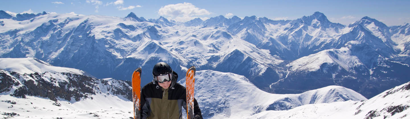 Skier standing in snow mountain landscape with blue sky