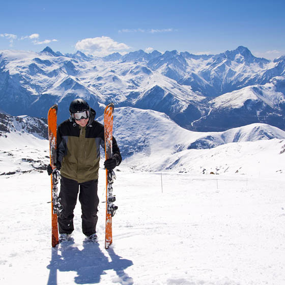 Skier standing in snow mountain landscape with blue sky